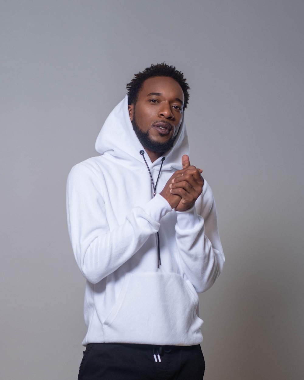 Lova Jah, les mains jointes, en sweat blanc